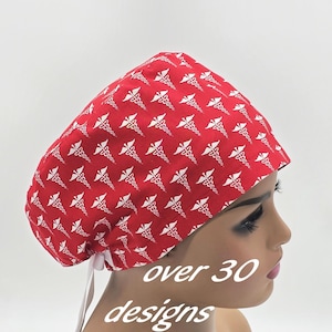 Peut inclure: Bonnet de chirurgien rouge avec un motif de caducée blanc. Le bonnet est noué dans le dos avec des liens blancs. Le texte "over 30 designs" est affiché sur l'image.