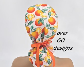 May include: A light pink scrub cap with a vibrant orange and green citrus fruit pattern. The cap is tied with an orange ribbon. Text on the side reads "over 60 designs".