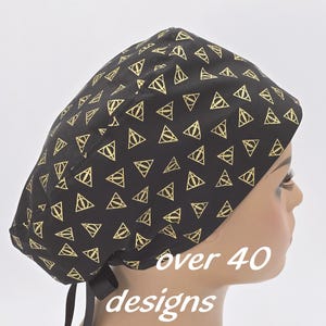 May include: Black surgical scrub cap with a gold geometric pattern. The cap features a tie in the back for an adjustable fit. Text on the image reads "over 40 designs".