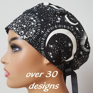 May include: Black and white patterned surgical scrub cap featuring a celestial design with moons, stars, and constellations. The cap has a tie in the back and the text "over 30 designs" is visible.