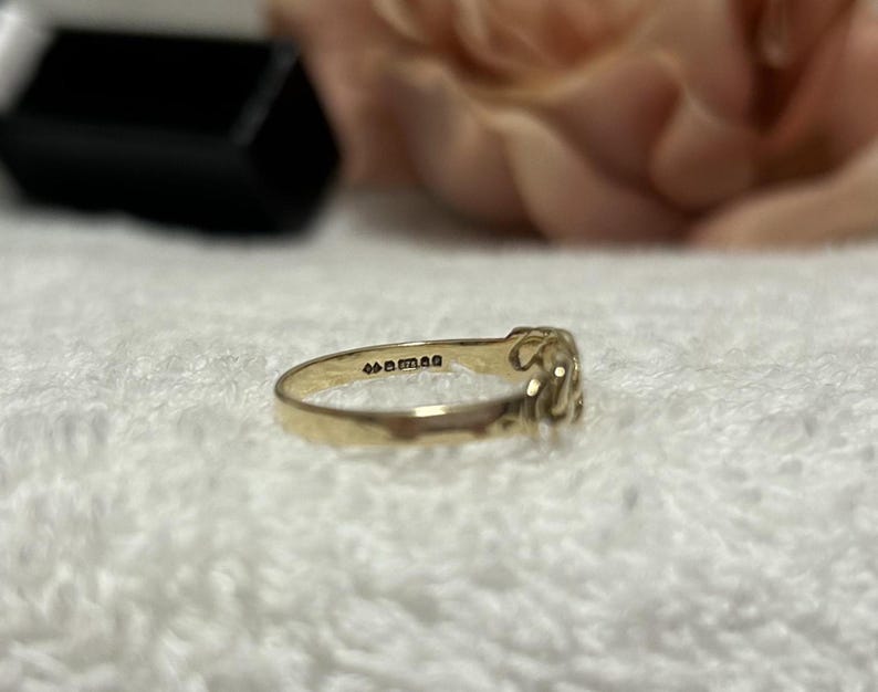 May include: A gold ring with an ornate design. The ring is set against a soft, white background. The ring has the text "44man" engraved on the inside.