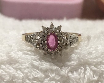 Pode incluir: Um anel de ouro com uma gema oval rosa cercada por um halo de diamantes menores.