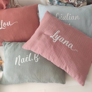 K&ouml;nnte beinhalten: Drei dekorative Kissen in Rosa und Gr&uuml;n mit wei&szlig;en Stickereien der Namen: Lou, Lyana und Na&euml;l.B.