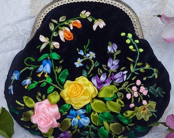 May include: A black velvet purse with a silver clasp and floral embroidery. The embroidery features a variety of colors, including pink, yellow, green, and blue.