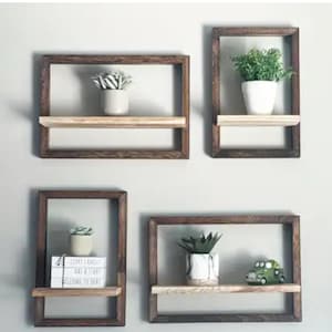 May include: Four wooden wall shelves with a light brown stain. Each shelf has a single, thin, light wood shelf. The shelves are empty except for two shelves that have small potted plants and one shelf that has a stack of three books and a small toy car.
