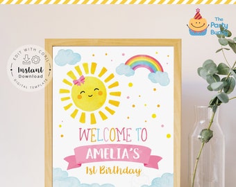 May include: A printable welcome sign for a first birthday party. The sign features a cartoon sun with a pink bow, a rainbow, and clouds. The text reads "Welcome to Amelia's 1st Birthday".