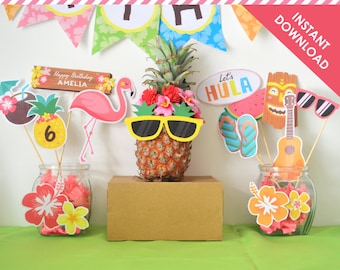 Puede incluir: Decoraciones de centro de mesa para una fiesta de luau con una piña con gafas de sol, un flamenco, un coco, un cartel que dice "Feliz cumpleaños Amelia", un cartel que dice "Let's Hula", una máscara tiki, un ukelele y chanclas.