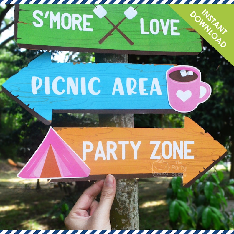May include: Three wooden signs with arrows pointing in different directions. The top sign is green and says "S'more Love". The middle sign is blue and says "Picnic Area" with a pink mug with marshmallows and a heart on it. The bottom sign is orange and says "Party Zone" with a pink tent.