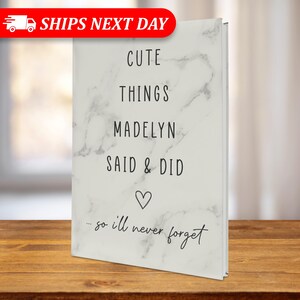 May include: A white marble-patterned journal with the text "Cute Things Madelyn Said & Did...so I'll never forget" in black lettering and a small heart symbol.