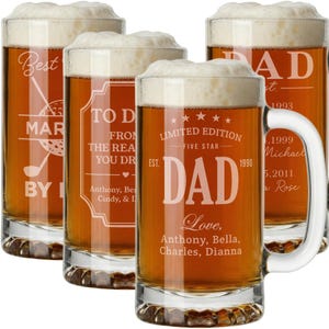 May include: Four clear glass beer mugs filled with beer and topped with foamy white heads. Each mug has a different engraved message, including "DAD" and personalized names and dates. The mugs have handles and are filled with amber-colored beer.