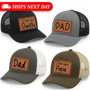 May include: Four trucker hats in black, gray, olive green, and brown. Each hat has a mesh back and a rectangular patch with text: "I love you Daddy", "DAD", "Dad", and "I love you Papa".