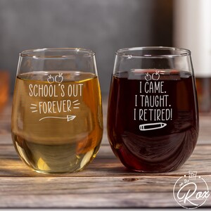 May include: Two stemless wine glasses with white text on a wood background. The glass on the left says "School's Out =Forever=." The glass on the right says "I Came. I Taught. I Retired!"