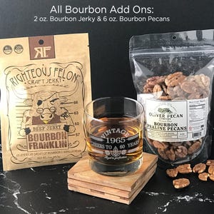 May include: A set of bourbon-flavored snacks, including a bag of bourbon jerky with a cartoon bull on the packaging, a bag of bourbon pecan pralines, and a glass with the text "Vintage 1965 Cheers to 60 Years".