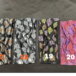 May include: Four black fabric headbands with a repeated pattern of the Harley Davidson logo and skull. The headbands are numbered 17, 18, 19, and 20.