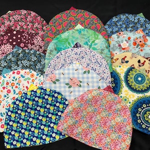 May include: A collection of 14 colorful fabric hats with various patterns, including floral, geometric, and abstract designs. The hats are all made of cotton and are perfect for adding a touch of personality to any outfit.