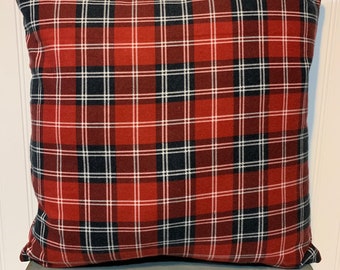 May include: Red, black, and white plaid throw pillow. The pillow is made of a soft, woven fabric.