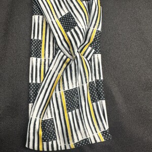 May include: A black and white headband with a thin yellow stripe pattern. The pattern is a repeated design of American flags with a yellow stripe across the middle.