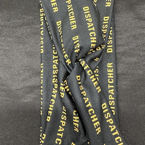 May include: Black headband with the words "Dispatcher" repeated in gold lettering.