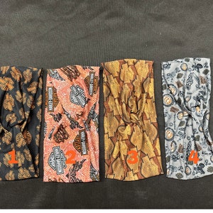 May include: Four different fabric headbands with a Harley Davidson logo pattern. The headbands are in black, orange, gold, and gray.
