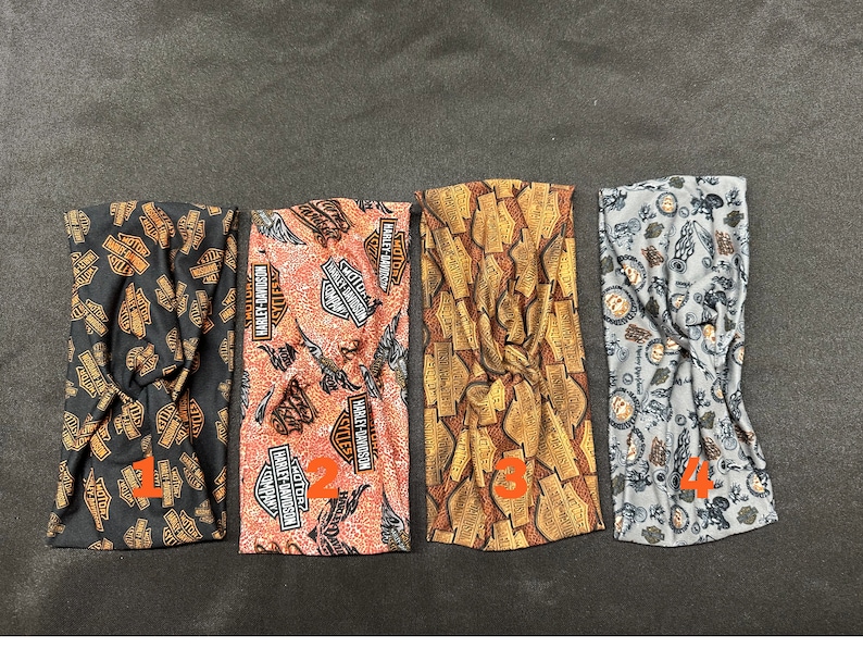 May include: Four different fabric headbands with a Harley Davidson logo pattern. The headbands are in black, orange, gold, and gray.