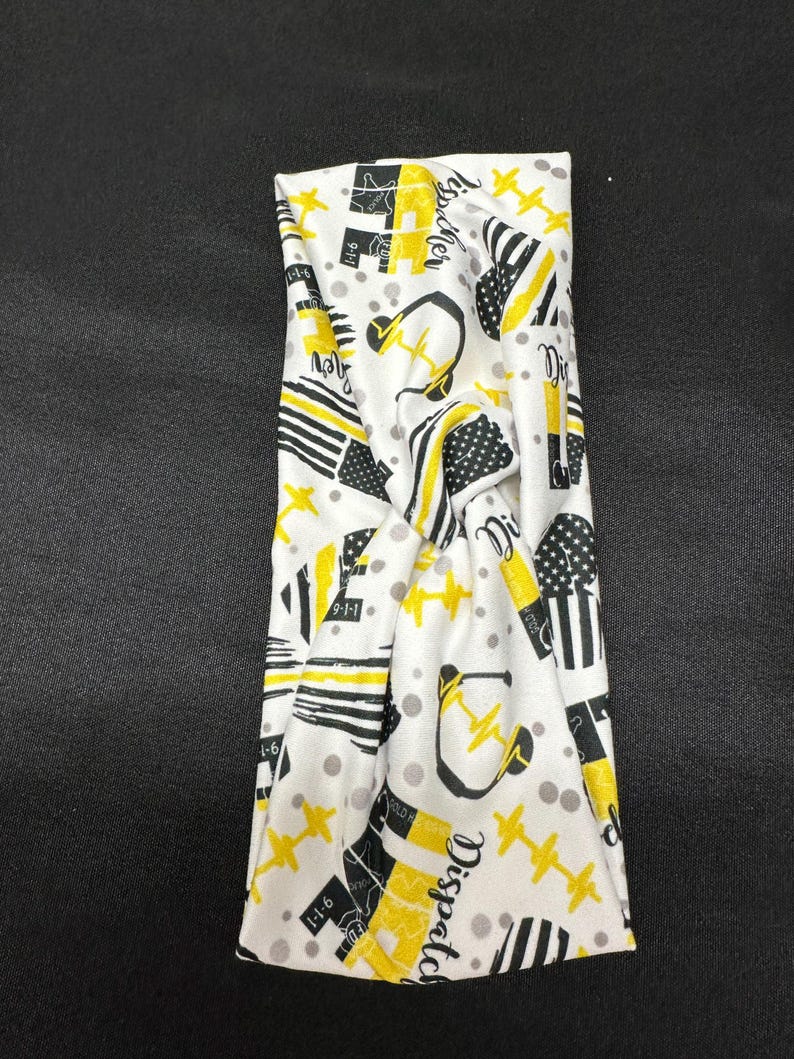 May include: White and yellow patterned headband with the word "Dispatcher" and other symbols, including a headset, a star, and a thin yellow line.
