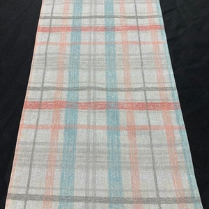 May include: A white table runner with a plaid pattern in shades of light blue, pink, and gray.