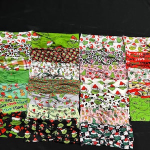 May include: A collection of twenty-four fabric headbands featuring various patterns of the Grinch character, including green, red, white, and black color schemes. The headbands display festive holiday motifs, text reading STINK STANK STUNK, and character faces wearing Santa hats in a variety of printed designs.