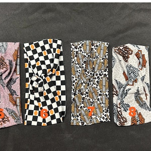 May include: Four different patterned headbands with a knot design. The headbands feature a black and white checkered pattern, a leopard print with Harley Davidson logos, a pink and brown pattern with Harley Davidson logos, and a white and brown pattern with Harley Davidson logos.