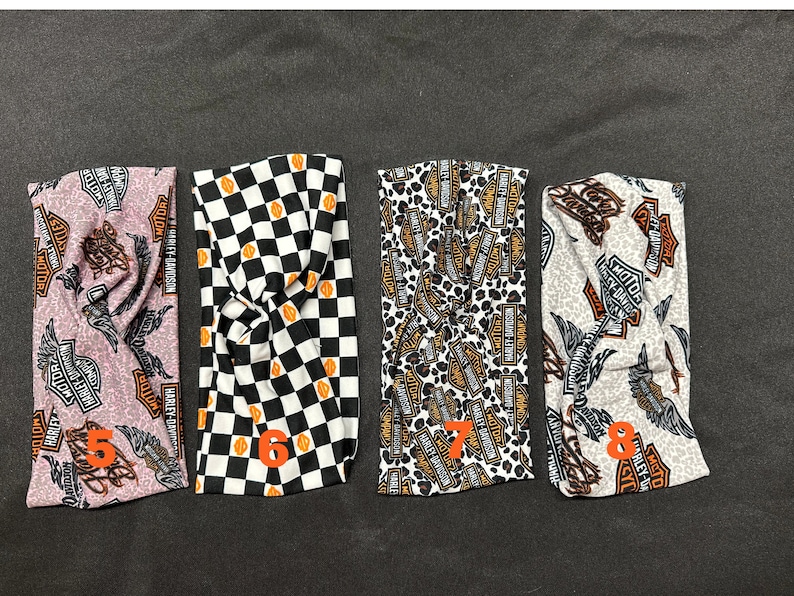 May include: Four different patterned headbands with a knot design. The headbands feature a black and white checkered pattern, a leopard print with Harley Davidson logos, a pink and brown pattern with Harley Davidson logos, and a white and brown pattern with Harley Davidson logos.