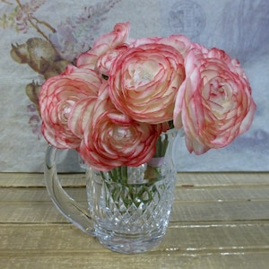 K&ouml;nnte beinhalten: Ein Strau&szlig; rosa und wei&szlig;er Ranunkeln in einer klaren, geschliffenen Glaskaraffe mit Diamantenmuster.