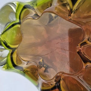 May include: A glass bowl featuring a multi-lobed, organic shape with a gradient color transition from a deep amber center to a vibrant lime green rim. The thick, transparent glass has a smooth, polished surface with distinct curved indentations.