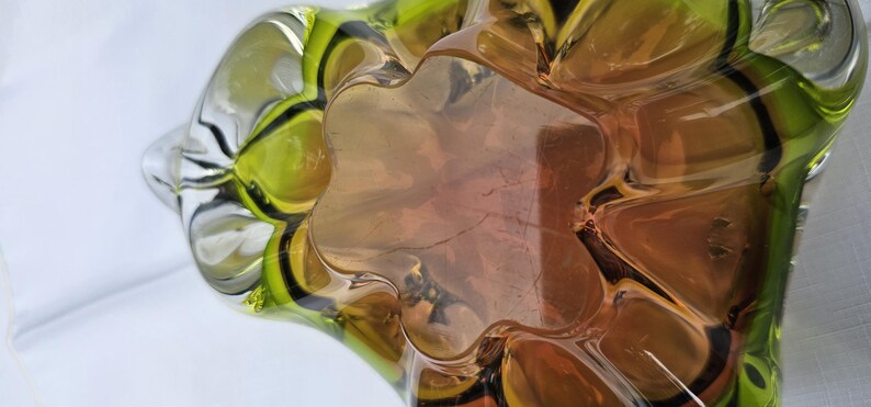 May include: A glass bowl featuring a multi-lobed, organic shape with a gradient color transition from a deep amber center to a vibrant lime green rim. The thick, transparent glass has a smooth, polished surface with distinct curved indentations.
