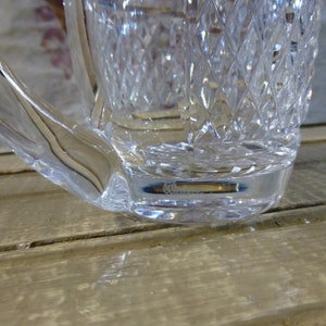 K&ouml;nnte beinhalten: Eine klare Glaskaraffe mit geschliffenem Glasdesign. Der Boden der Karaffe hat eine kleine ge&auml;tzte Markierung mit der Aufschrift "CCO."