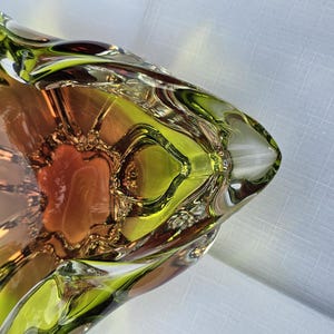 May include: A decorative glass bowl featuring a vibrant lime green outer rim that transitions into a warm amber and orange center. The bowl has a distinct triangular shape with undulating, ruffled edges and a smooth, polished finish throughout.
