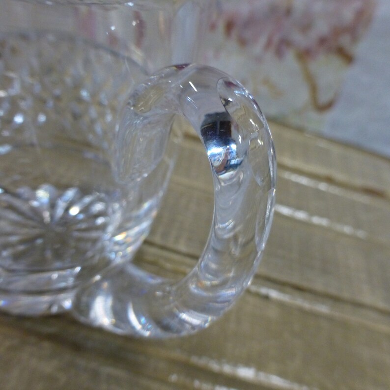 K&ouml;nnte beinhalten: Eine klare Glas Tasse mit einem dekorativen Muster und einem dicken, gedrehten Griff.