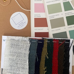 May include: A brown paper envelope with a white circular sticker labelled Framed Notice Board Company, three paint colour sample cards featuring various shades, and a rectangular card displaying a row of multi-coloured fabric swatches.