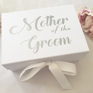 May include: White gift box with a silver ribbon and the text "Mother of the Groom" printed on the top.