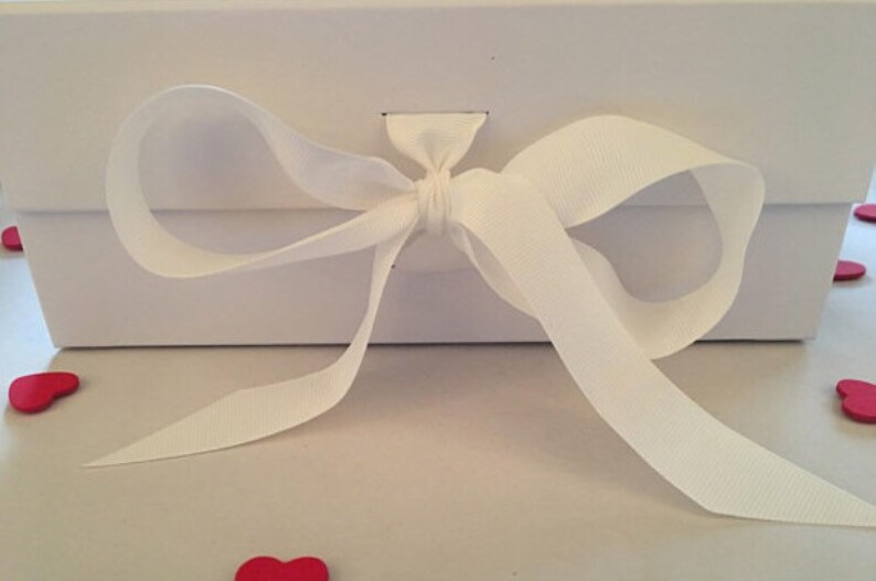 May include: A white gift box with a white satin ribbon tied in a bow.