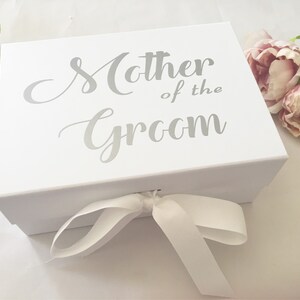 May include: White gift box with a silver ribbon and the text "Mother of the Groom" printed on the top.