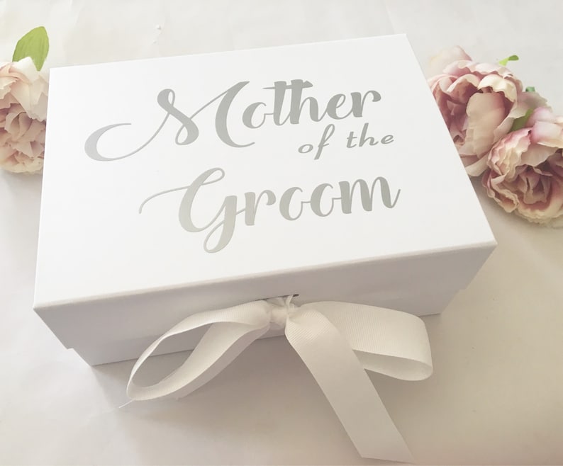 May include: White gift box with a silver ribbon and the text "Mother of the Groom" printed on the top.