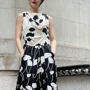 May include: A sleeveless black and white floral print dress with a gathered bodice and a knee-length skirt.