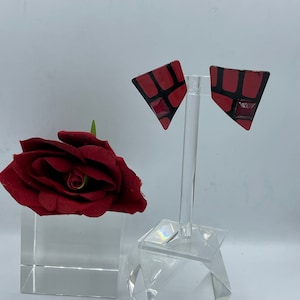May include: A pair of red and black geometric triangle shaped earrings with a small red square in the center of each earring.