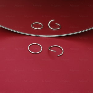 May include: Four silver nose rings on a red surface. Two of the nose rings are closed circles and two are open circles.