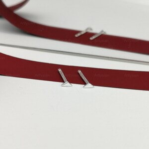 May include: Two silver triangle shaped earrings with posts