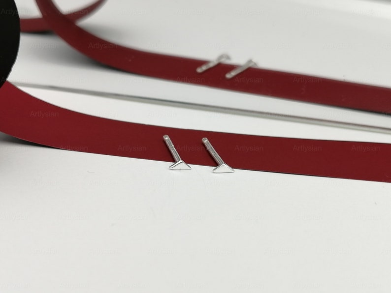 May include: Two silver triangle shaped earrings with posts
