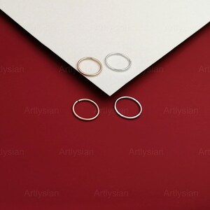 May include: Four hoop earrings, two silver and two gold, displayed on a white surface against a red background.