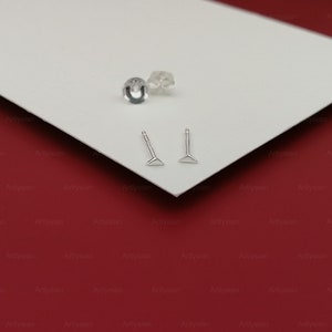 May include: Two silver triangle-shaped earrings with a post and a small silver backing.