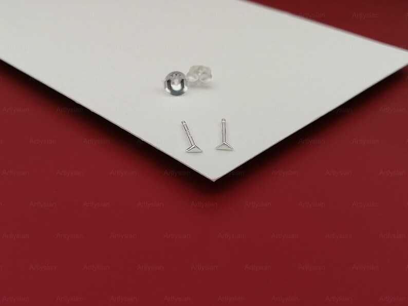 May include: Two silver triangle-shaped earrings with a post and a small silver backing.