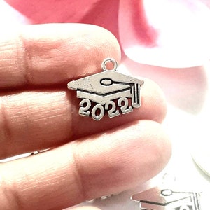 May include: Silver charm with a graduation cap and the year 2022.