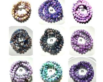 May include: Nine circular strands of round beads labeled 67 through 75. The beads feature marbled patterns in various colors including yellow, purple, blue, black, pink, and teal. Each strand is arranged in a coil on a white background.
